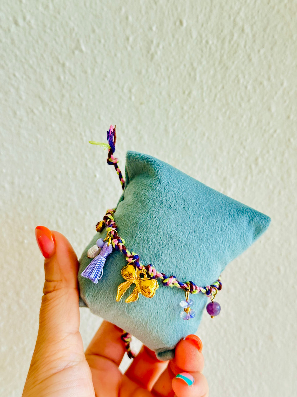 Pulsera de hilo violeta con charms de lazo, flor y más