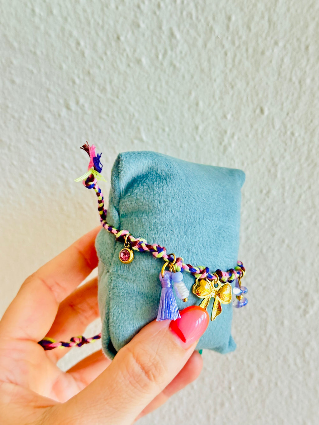 Pulsera de hilo violeta con charms de lazo, flor y más