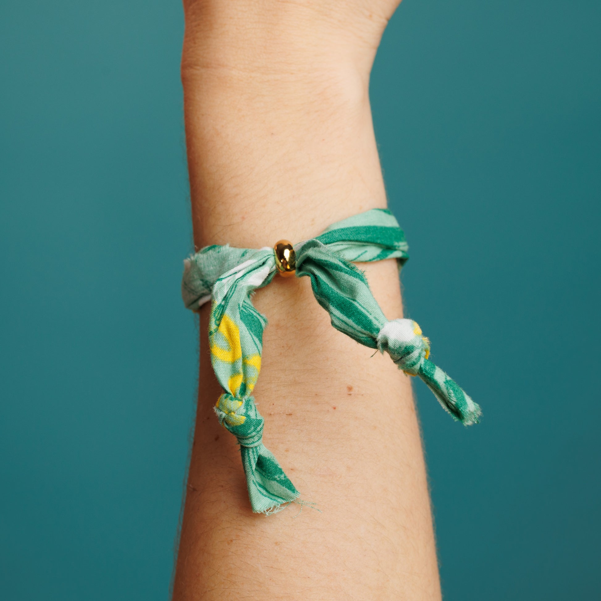 Pulsera de tela verde con charms de corazón, flor y hilo